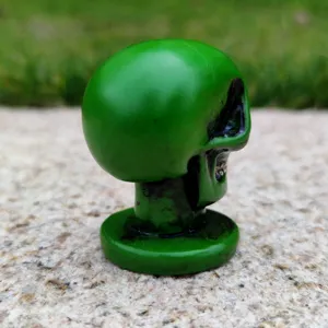 Green skull figurine close up, Halloween spooky ornament, sandplay toy detail view.