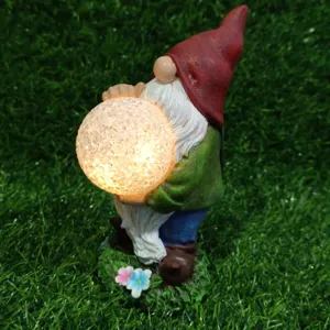 Close-up of solar garden gnome holding glowing cracked glass ball, resin figurine light decor.
