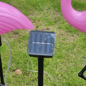 Detail view of outdoor solar flamingo lawn light solar panel and pink garden stake decor.