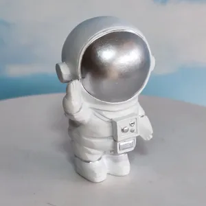 Astronaut figurine detail shot, featuring silver reflective visor and cute waving pose for decor.