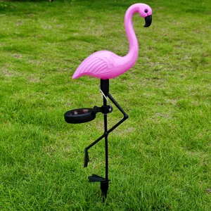 Close-up detail of pink flamingo solar garden light placed on green lawn outdoor decor.