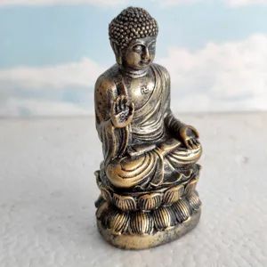 Detailed shot of miniature bronze Buddha statue sitting on lotus base, religious artifact decor.