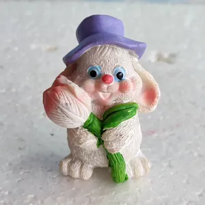 Vista dettagliata di una simpatica statuetta di coniglietto di pasqua in resina con fiore.