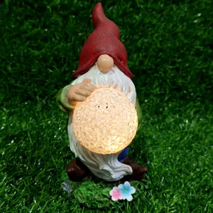 Solar garden gnome resin figurine holding glowing cracked glass ball for outdoor decor.
