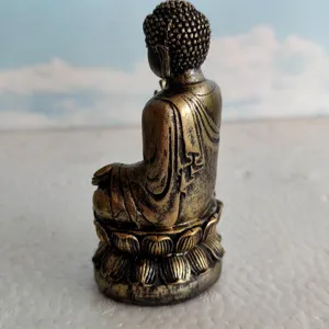 Detailed view of a miniature bronze-colored Buddha statue on a lotus base for sand tray therapy.