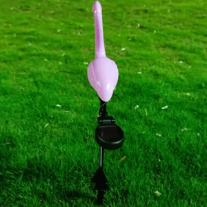 Detailed close-up of pink flamingo solar garden light staked in green lawn for outdoor decor.