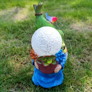Detail view of solar garden resin gnome statue holding cracked glass ball light.