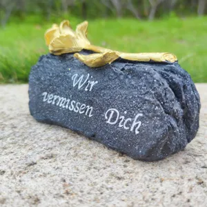 Memorial grave stone with golden rose and German text, perfect outdoor tribute decoration.