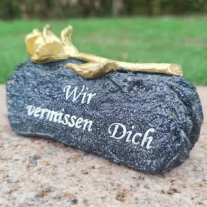 Detail view of a memorial grave stone ornament featuring a golden rose and engraved German text.