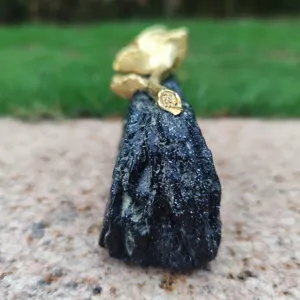 Memorial grave ornament detail, black stone base with golden flower for cemetery mourning.