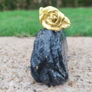 Detailed view of the golden rose memorial grave ornament on stone base, outdoor scene closeup.