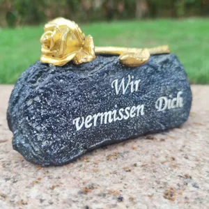 Grave memorial stone detail shot showing golden rose decoration and german condolence text.