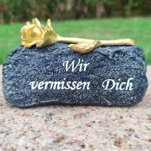 Memorial grave stone decoration with golden rose, outdoor cemetery memorial ornament detail.