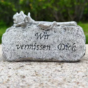 Memorial stone grave ornament with rose sculpture and German engraving, outdoor garden decor detail.
