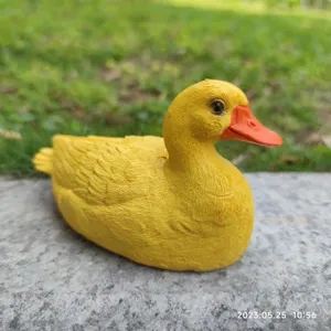 Detailed close-up of a resin yellow duck garden sculpture, showing realistic texture.