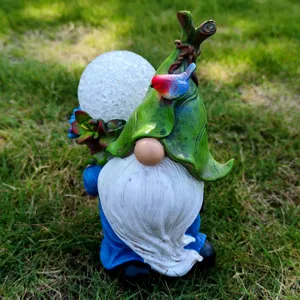 Closeup of solar garden gnome resin sculpture detail with cracked glass globe light and bird.