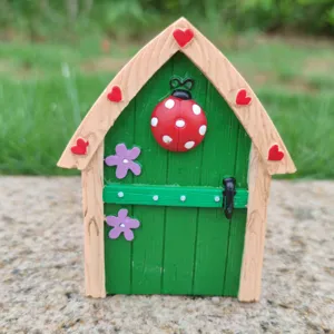 Primer plano de puerta de hadas en miniatura de resina con mariquita y corazones lindos.