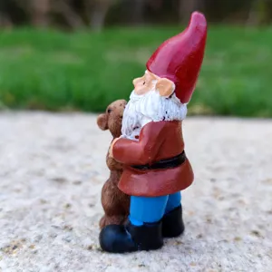 Gedetailleerd close-upzicht van een miniatuur tuinkabouter-figuur die een dier knuffelt.