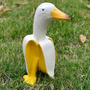 Creative banana duck figurine close-up, fun resin garden ornament on green grass background