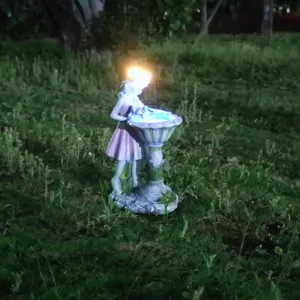 Detail view of the resin fairy solar garden light glowing softly on outdoor grass at night.