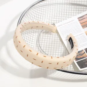 Vue détaillée du serre-tête beige rembourré avec joli motif d'ours, accessoire de cheveux doux.