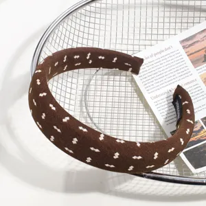 Gros plan détaillé d'un serre-tête large en tissu marron avec motifs et étiquette.