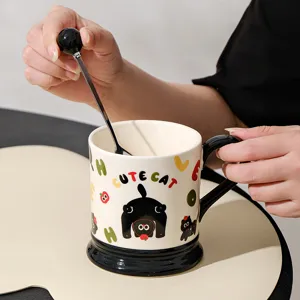 Ceramic coffee mug with cute black cat print and spoon, stylish drinkware for home office.