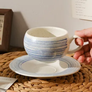 Keramische koffiekop detail met blauwe penseelstreken op rustiek crèmewit geglazuurd keramiek.
