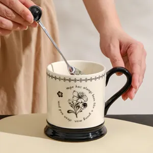 Gedetailleerd overzicht van de keramische mok met zwarte voet, handvat en elegante bloemmotief.
