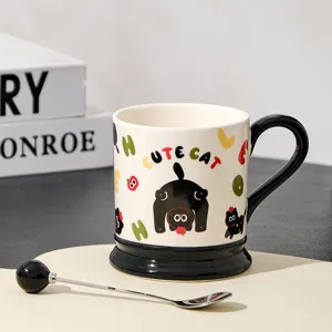 Ceramic coffee mug with cute black cat pattern and matching spoon for home kitchen use.