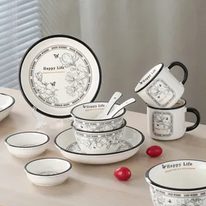 Ceramic tableware set detail showing plates, bowls, and mugs with elegant black floral patterns.