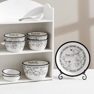 Ceramic tableware set detail showing bowls and plates with black rims and floral patterns.