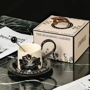 Retro keramische koffiekop en schotel detailopname, elegant zwart-wit bloemdesign met geschenkdoos.