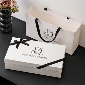 Gedetailleerd uitzicht op een elegante witte geschenkdoos en bijpassende tas met zwart lint.