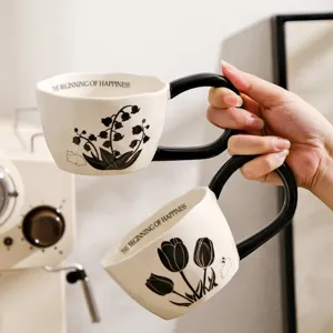 Close-up detail of creative ceramic coffee mug with black handle and botanical pattern.