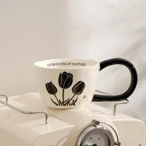 Ceramic coffee mug detail shot featuring retro tulip illustration and sleek black handle design.