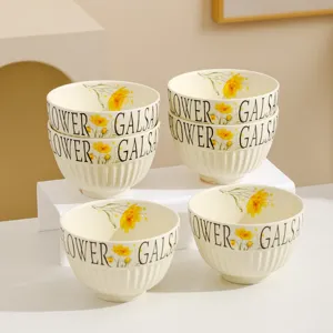 Detailed view of cream ceramic bowl featuring yellow floral pattern and ribbed texture.