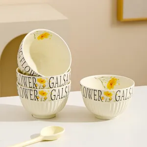 Close-up detail of cream ceramic rice bowl set with yellow flower print and vertical stripes design.
