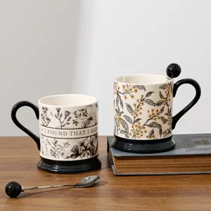 Vintage ceramic coffee mug with black handle and spoon, exquisite floral detail for office use.