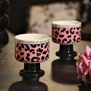 Nahaufnahme der Keramik-Hochstielkerzentasse mit rosa Leopardenmuster und schwarzem Fuß.