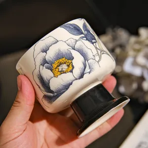 Detailansicht einer Keramik-Hochstiel-Tasse mit blauem Blumenmuster und schwarzem Fuß.