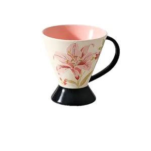 Tazza da caffè in ceramica con motivo floreale di giglio rosa in rilievo, base alta e manico elegante.