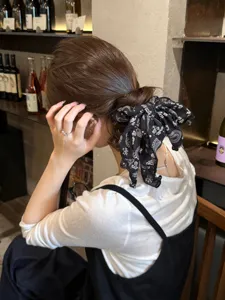 Vista detallada del coletero para el pelo con cinta estampada de cachemir negro y blanco en escena.