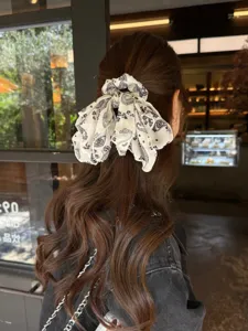 Coletero de pelo vintage con estampado paisley y cinta larga, lazo negro y blanco elegante.