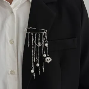 Detailed view of silver metal safety pin brooch with hanging chains, pearls and charms.