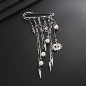 Punk style silver safety pin brooch detail featuring chains, pearls, spikes and evil eye pendant.