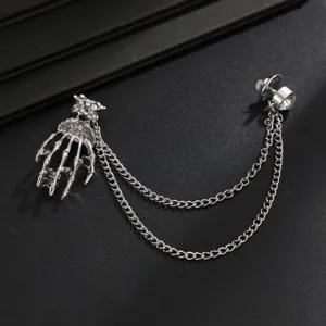 Silver rhinestone skeleton hand brooch with double chains, trendy men's suit accessory.