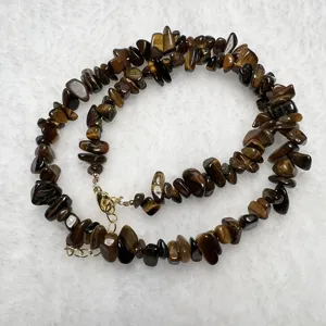 Primo piano di una collana in chips di pietra occhio di tigre naturale con chiusura dorata.