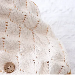 Nahaufnahme der Strick-Haustierpullover-Details mit beigem Rautenmuster und Holzknopf.