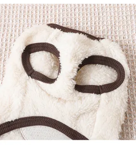 Close-up detail of warm white fluffy fleece pet vest featuring brown ribbed trim for small dogs.